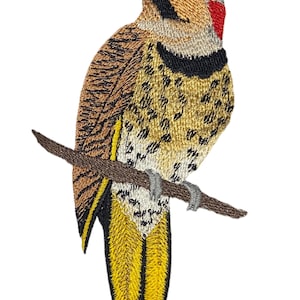 以下が含まれることがあります： 枝にとまっているキツツキの刺繍パッチ。鳥は茶色、黄色、黒、赤のディテールが特徴です。鳥の翼は黒い模様の茶色で、尾は黄色です。パッチは白い背景にあります。