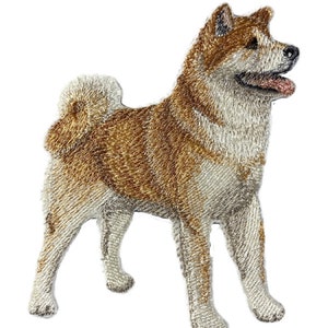 Puede incluir: Parche bordado de un perro Akita en posición de pie. El perro tiene un pelaje marrón claro y blanco con costuras detalladas. El parche está sobre un fondo blanco, mostrando las características del perro.
