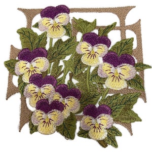 Puede incluir: Diseño bordado de un motivo floral con un grupo de pensamientos morados y amarillos con hojas verdes, enmarcado en marrón.