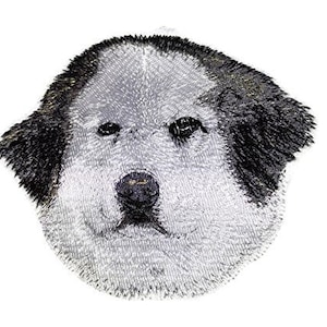 Puede incluir: Parche bordado de un perro de montaña de los Pirineos con pelo blanco y negro. El perro mira directamente al espectador con la lengua ligeramente fuera.