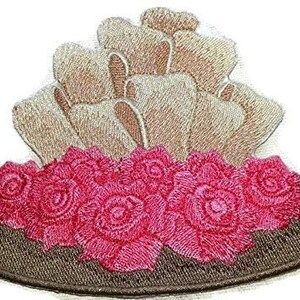 May include: Embroidered iron-on patch featuring a brown hat with a cluster of pink roses and a beige flower arrangement on top.