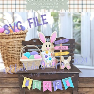 May include: A wooden Easter bunny bench with a basket of colourful eggs, a bunny rabbit figurine, and a sign that says "Bunny Trail", "Egg Hunt", and "Hip Hop". The bench also has a banner that says "HOP" with bunny ears on each end.
