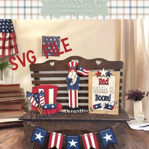 May include: A wooden bench with a red, white and blue gnome, a sign that says "Red White & Boom!" and a banner with stars and stripes. The gnome is wearing a red, white and blue hat and holding a flag. The sign is framed in wood and has a red, white and blue star on each corner. The banner is made of fabric and has a star on each flag.