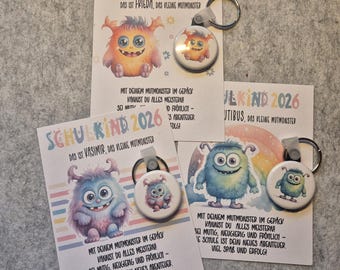 May include: Cards and keychains featuring colorful cartoon monsters. The cards read "SCHULKIND 2026" and include text in German. The keychains have matching monster designs. The theme is likely related to school or children.