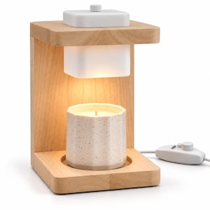 May include: A light wood candle warmer lamp with a white rectangular heating element and a white cord featuring a rotary dimmer switch. A speckled off-white ceramic candle vessel with a scalloped edge sits on the base beneath the light.
