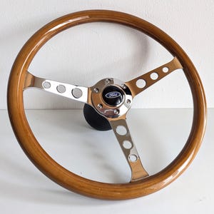 May include: A wooden steering wheel with a chrome center and spokes. The center has a Ford logo.