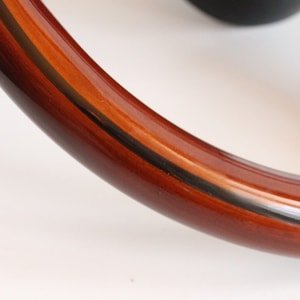 Puede incluir: Primer plano de un volante de madera marr&oacute;n con un detalle de rayas blancas y negras.
