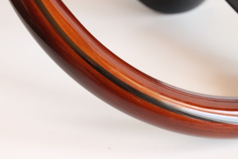 Puede incluir: Primer plano de un volante de madera marr&oacute;n con un detalle de rayas blancas y negras.