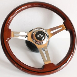 May include: A brown wood steering wheel with a black and chrome center hub. The hub has a silver "MINI" logo.