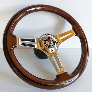 May include: A brown wood steering wheel with a chrome center and three chrome spokes. The center has a black and chrome Volkswagen logo.