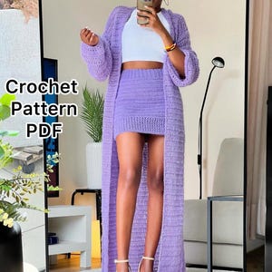 Puede incluir: Un conjunto de crochet lila que consta de un cárdigan largo, una minifalda y un top corto blanco. El texto "Crochet Pattern PDF" es visible en la imagen. El conjunto se usa con tacones nude.