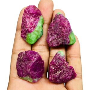 May include: Four rough, unpolished ruby zoisite stones with a distinct color combination of deep magenta-pink and vibrant lime green. Each mineral specimen features an irregular, jagged texture and crystalline structure with varying color distribution.