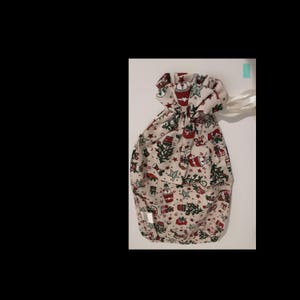 May include: A white fabric gift bag with a drawstring closure. The bag is decorated with a Christmas-themed print featuring red and green baubles, stars, and trees.
