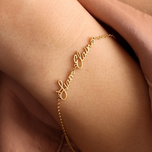 May include: A gold chain bracelet with the names "Liam" and "Elaine" written in cursive.