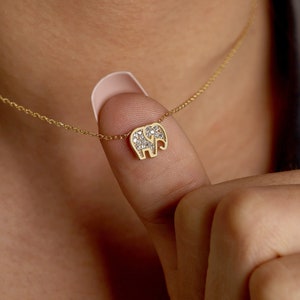 May include: A gold chain necklace with a small, diamond-encrusted elephant pendant.