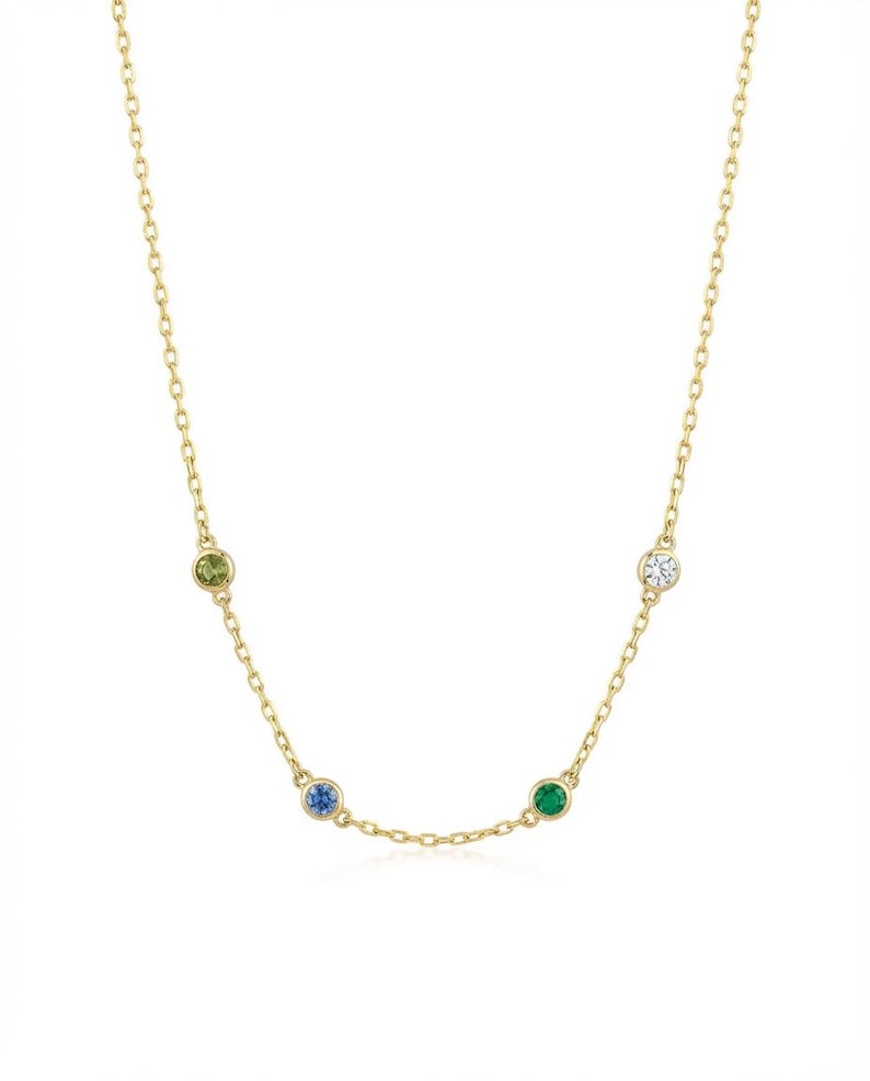 May include: A delicate gold necklace featuring a chain with four colorful gemstones: a light green, a blue, a green, and a clear stone. The necklace is a simple, elegant design, perfect for everyday wear.