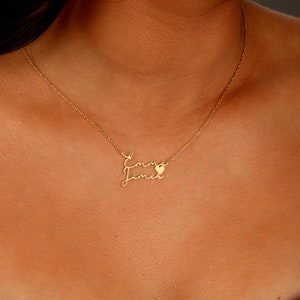 May include: Gold necklace with two names, "Emma" and "James", written in cursive script with a small heart charm between the names.