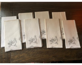 May include: Set of eight white linen napkins with grey embroidered floral designs.
