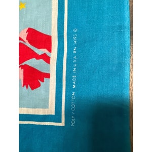 May include: Close-up of a blue fabric with white trim and the text "POLY/COTTON MADE IN USA RN 14193 O"