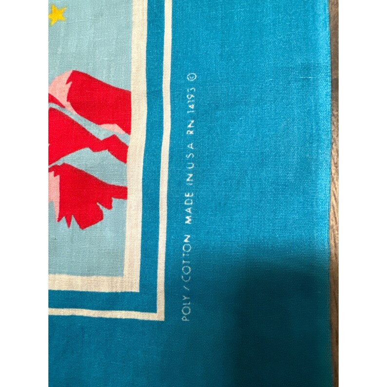 May include: Close-up of a blue fabric with white trim and the text "POLY/COTTON MADE IN USA RN 14193 O"