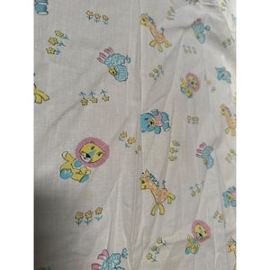 May include: White fabric with a repeating pattern of cartoon animals, including lions, giraffes, sheep, and bears. The animals are in pastel colors, with yellow, pink, and blue accents. Small yellow flowers are scattered throughout the design.