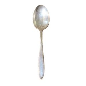 May include: A silver spoon with a rounded bowl and an ornate handle.