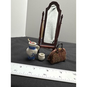 May include: A miniature dark wood cheval mirror, a white ceramic pitcher with blue floral accents, a small plain white ceramic pot, and a textured brown patterned handbag. A ruler is visible, showing the items are approximately 3 inches tall.