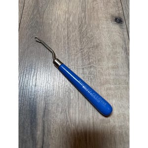 Op de afbeelding: Een knoophaak met een felblauw handvat en een zilverkleurige metalen haak. Op het handvat staat de tekst "Readicut" en "MADE IN ENGLAND" in reliëf. Het gereedschap heeft een slank, cilindrisch handvat en een gebogen metalen schacht.