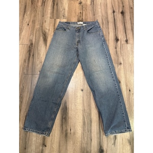 May include: Light blue denim jeans with a classic five-pocket design. The jeans have a relaxed fit and a button and zip closure. The denim has a faded wash, giving them a worn-in look.