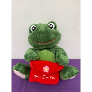 May include: Green plush frog holding a red envelope with a pink flower and the text "Just For You".