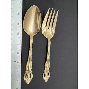May include: A set of two gold-plated cutlery pieces, a spoon and a fork, with ornate designs on the handles.