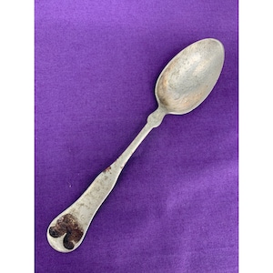 May include: A silver spoon with a heart-shaped design on the handle. The spoon is slightly tarnished and has a worn appearance.