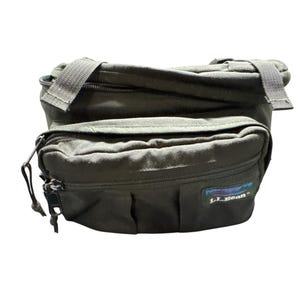 May include: A dark green L.L.Bean fanny pack with a zippered main compartment and a smaller zippered pocket on the front. The pack has a black adjustable strap.
