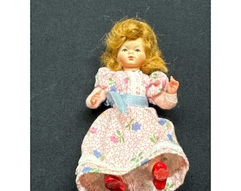 Muñeca vintage de 3” con cabello rojo, ojos azules, cara pintada, vestido floral y zapatos rojos