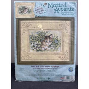 May include: A cross-stitch kit featuring a kitten and butterfly design. The kit includes a designer mat and is labeled as an easy weekend project. The finished piece measures 10 x 8 inches (25 x 20 cm).