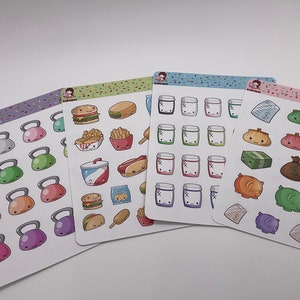 May include: Four sheets of stickers with various designs. One sheet features colorful kettlebells, another has food illustrations like burgers and fries, a third shows jars, and the last has purses and money.