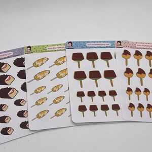 May include: Four sticker sheets with food illustrations. The stickers depict chocolate-covered ice cream bars, corn dogs, and chocolate-covered ice cream bars on sticks. Each sheet has a different coloured background.
