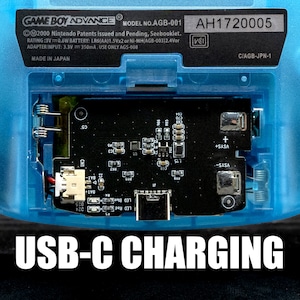 Puede incluir: Primer plano de una Game Boy Advance azul con un puerto de carga USB-C. El texto "USB-C CHARGING" est&aacute; impreso en blanco en la parte inferior de la imagen. El n&uacute;mero de serie "AH1720005" est&aacute; impreso en la esquina superior derecha de la imagen.