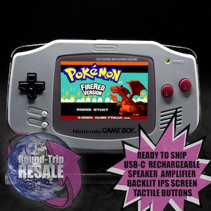 May include: A gray Game Boy Advance SP handheld gaming console with a bright pink background. The screen displays the Pokemon FireRed game title screen. The console has a USB-C port, a speaker amplifier, a backlit IPS screen, and tactile buttons.
