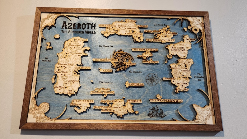 May include: A wooden map of the fictional world of Azeroth from the World of Warcraft video game. The map is framed in a dark wood frame and features the continents of Kalimdor, Eastern Kingdoms, Pandaria, and Zandalar. The map is detailed with various locations and landmarks, including the Maelstrom, the Great Sea, and the Wandering Isle.