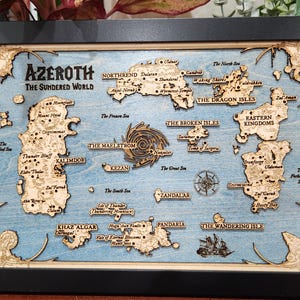 May include: A wooden map of the fictional world of Azeroth from the World of Warcraft video game. The map is framed in black and features a blue background with brown and white details. The map includes the names of various locations, including Kalimdor, Northrend, and Pandaria.