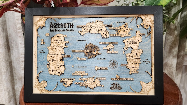 May include: A wooden map of the fictional world of Azeroth from the World of Warcraft video game. The map is framed in black and features a blue background with brown and white details. The map includes the names of various locations, including Kalimdor, Northrend, and Pandaria.