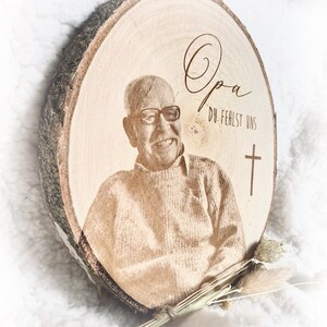 Puede incluir: Una placa conmemorativa de madera con una foto de un hombre y el texto "Opa Du fehlst uns" y una cruz.