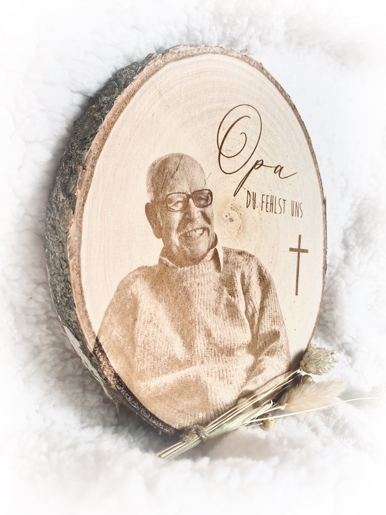 Puede incluir: Una placa conmemorativa de madera con una foto de un hombre y el texto "Opa Du fehlst uns" y una cruz.