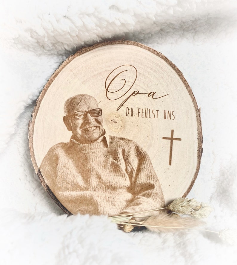 Puede incluir: Una placa conmemorativa de madera con una foto de un hombre y el texto "Opa Du Fehlst Uns" y una cruz.