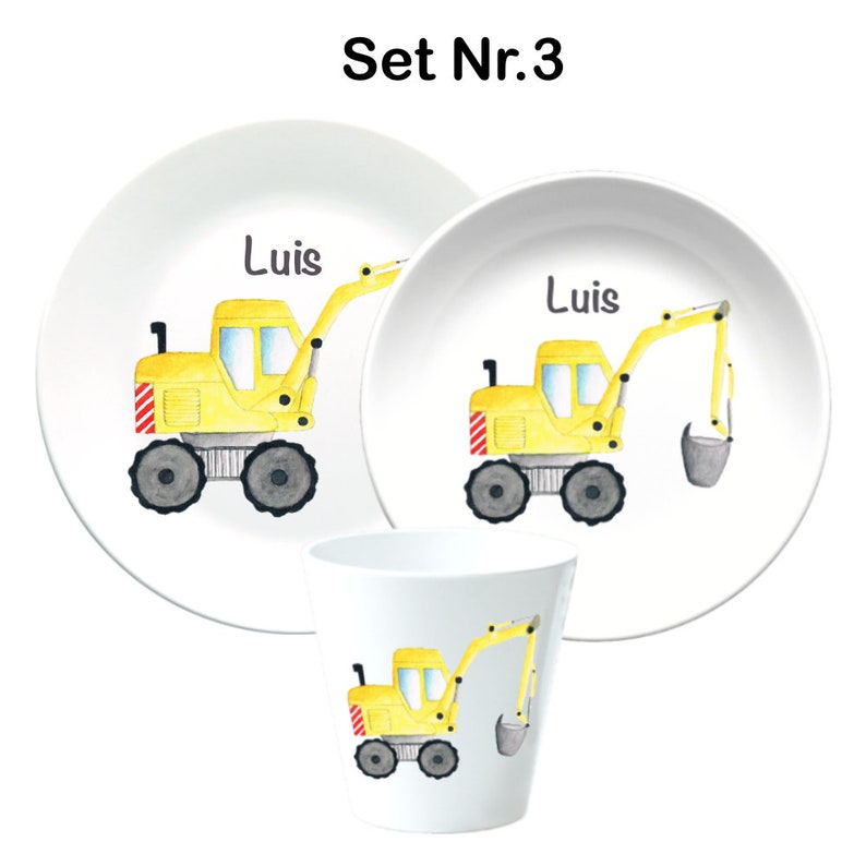 May include: A three-piece children's dinnerware set featuring a yellow excavator with a gray bucket. The set includes a large plate, a smaller plate, and a cup. The name "Luis" is printed on both plates.