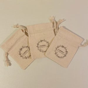 May include: Three small, off-white cotton drawstring bags with a floral design and the text "Craft & Home" printed on each bag.
