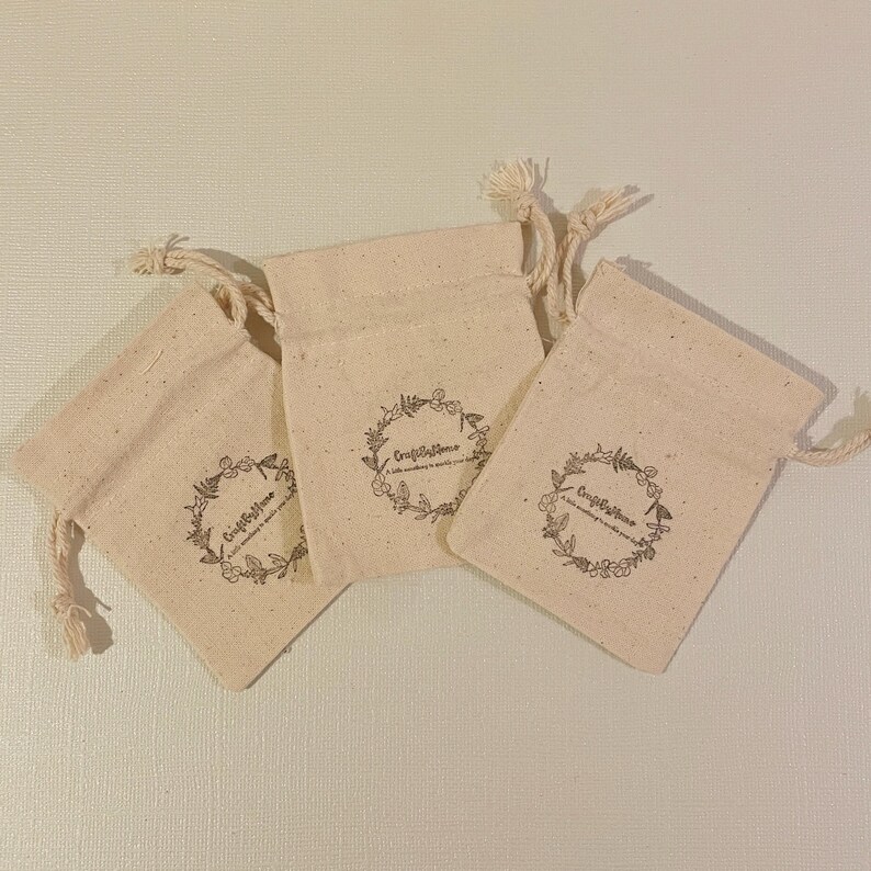 May include: Three small, off-white cotton drawstring bags with a floral design and the text "Craft & Home" printed on each bag.