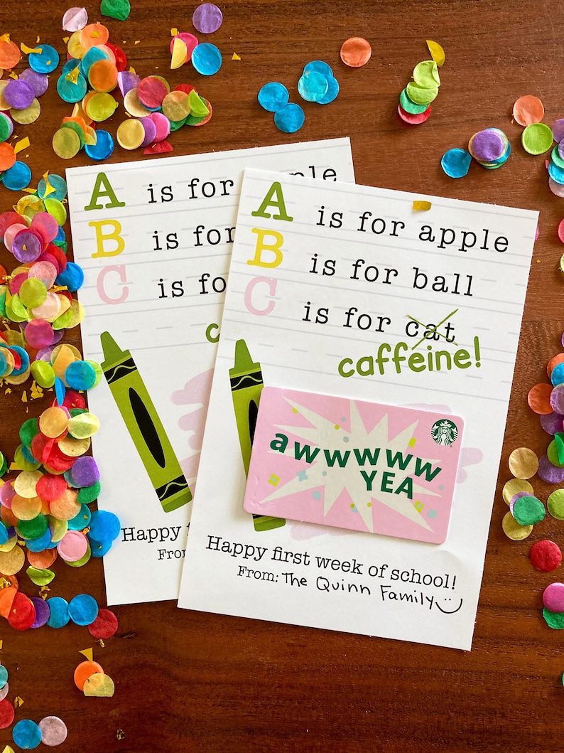 Puede incluir: Dos tarjetas rectangulares blancas con texto del alfabeto ABC, ilustraciones de crayones verdes y el texto A is for apple, B is for ball, C is for caffeine. Una tarjeta de regalo rosa de Starbucks con el texto awwwww YEA est&aacute; pegada.