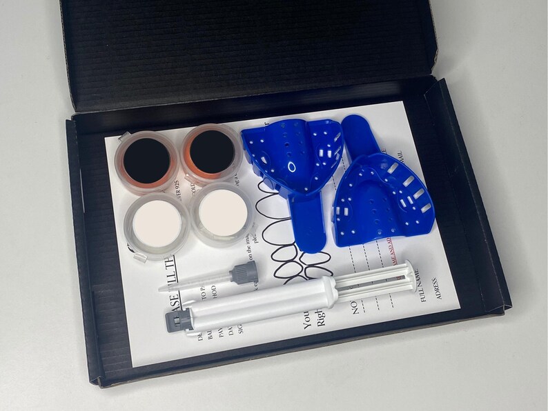 Peut inclure: Un kit pour r&eacute;aliser des empreintes dentaires &agrave; domicile. Il comprend deux plateaux bleus, deux bols de m&eacute;lange blancs, deux petits contenants de poudre brune et une seringue avec un piston blanc. Les instructions sur le papier disent "You Right", "No" et "Full Name Address".